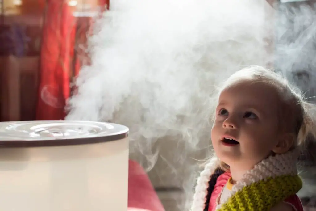 Child staring up at steam coming from a humidifier.